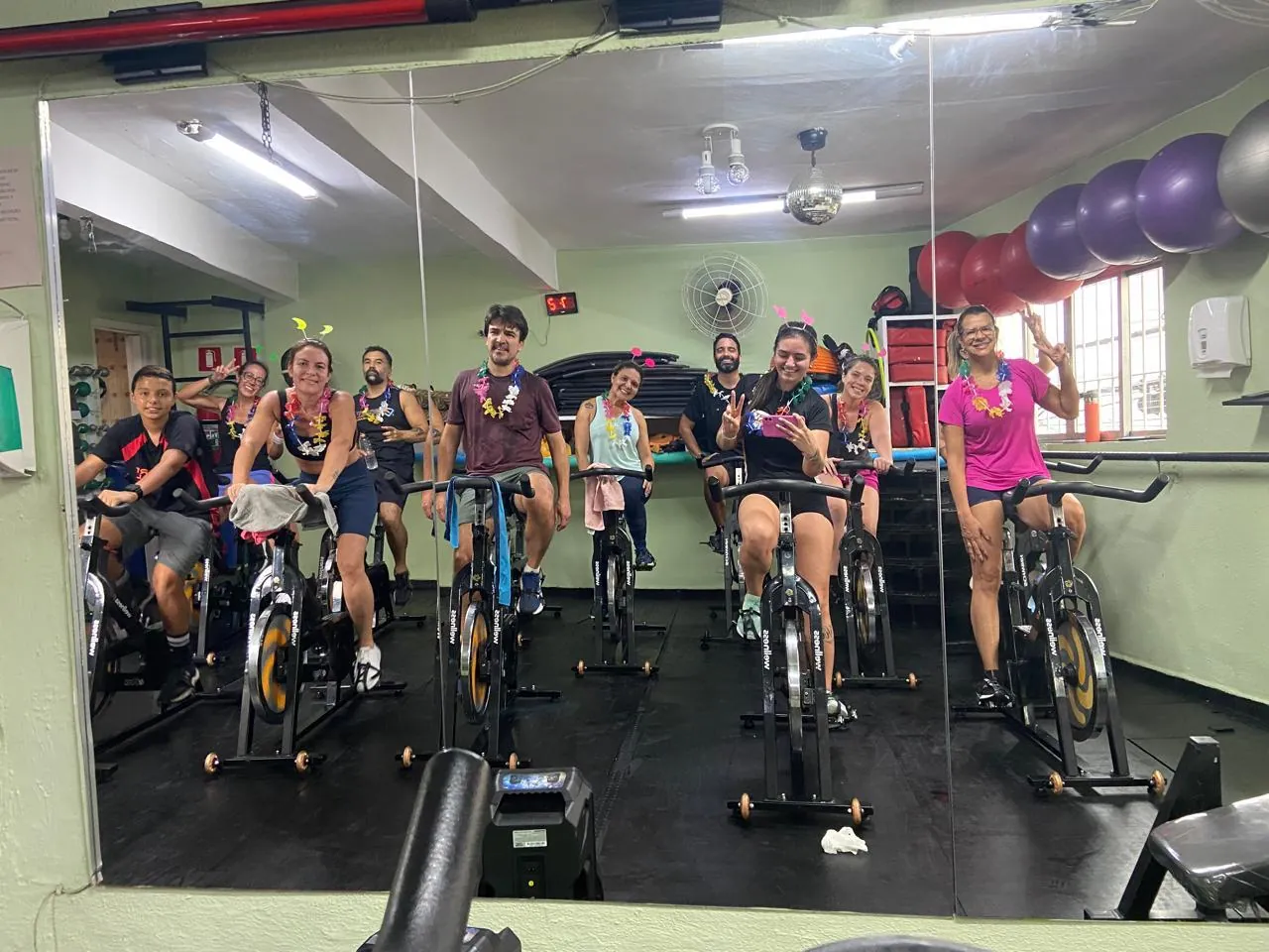 Sala de bike indoor vista pelo espelho, com a turma pedalando